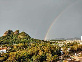 Low angle view of rainbow over trees against sky