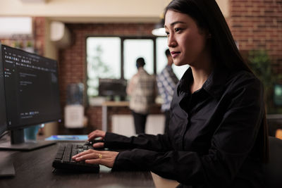 Portrait of young woman using laptop at office