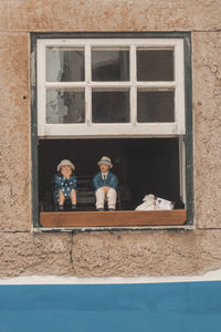 Portrait of man and woman seen through window of building