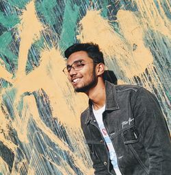 Portrait of young man standing against wall