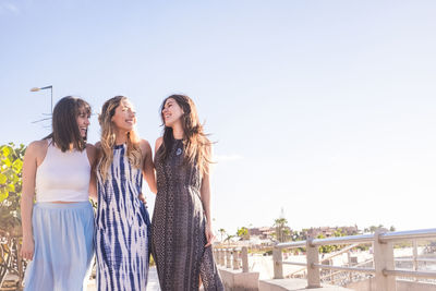 Friends standing against sky during sunny day