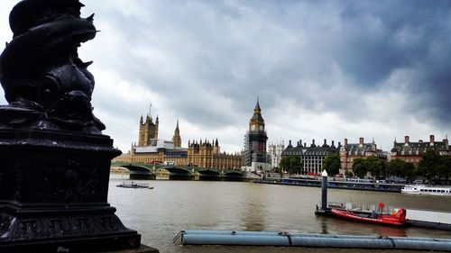 Buildings at waterfront against cloudy sky