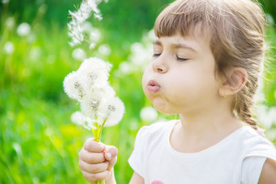 Close-up of girl blowing dandelion