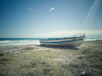 Boat moored on beach against sky
