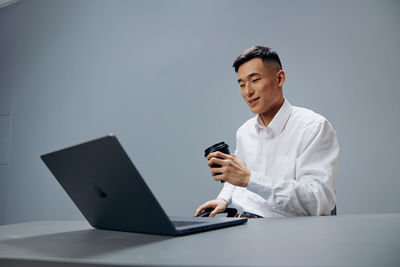 Portrait of doctor using mobile phone while sitting on table