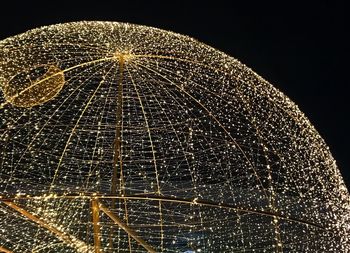 Low angle view of illuminated lighting equipment against black background