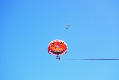 Low angle view of airplane flying against clear blue sky