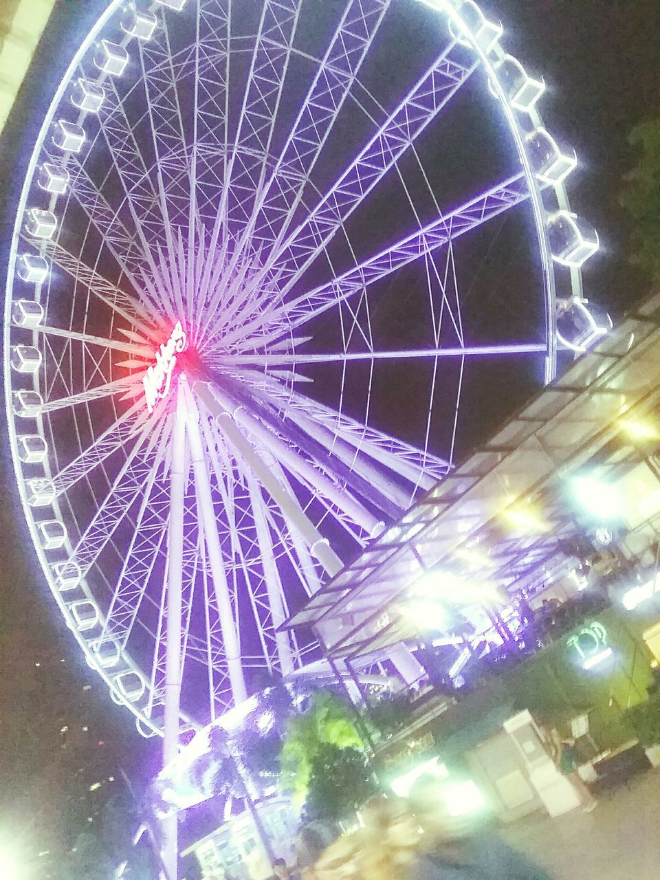 illuminated, night, arts culture and entertainment, built structure, long exposure, low angle view, architecture, ferris wheel, glowing, motion, firework display, amusement park ride, celebration, building exterior, amusement park, sky, sparks, blurred motion, circle, multi colored