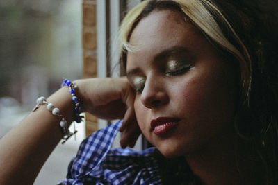 Close-up of young woman with eyes closed by window