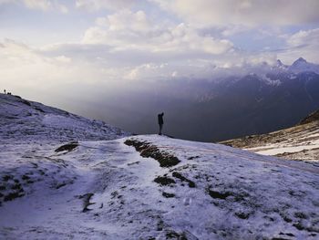 Full length of man standing on snowcapped mountain against sky