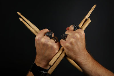 Close-up of hand holding cigarette over black background