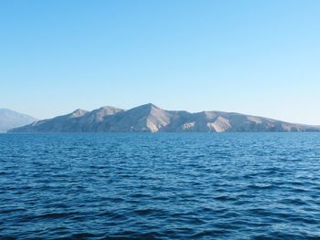 Scenic view of sea and mountains against clear blue sky