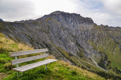 Empty bench on landscape against sky