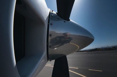 Reflection of man in airplane wing against sky