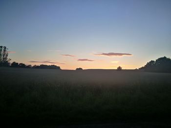 Scenic view of silhouette field against clear sky at sunset