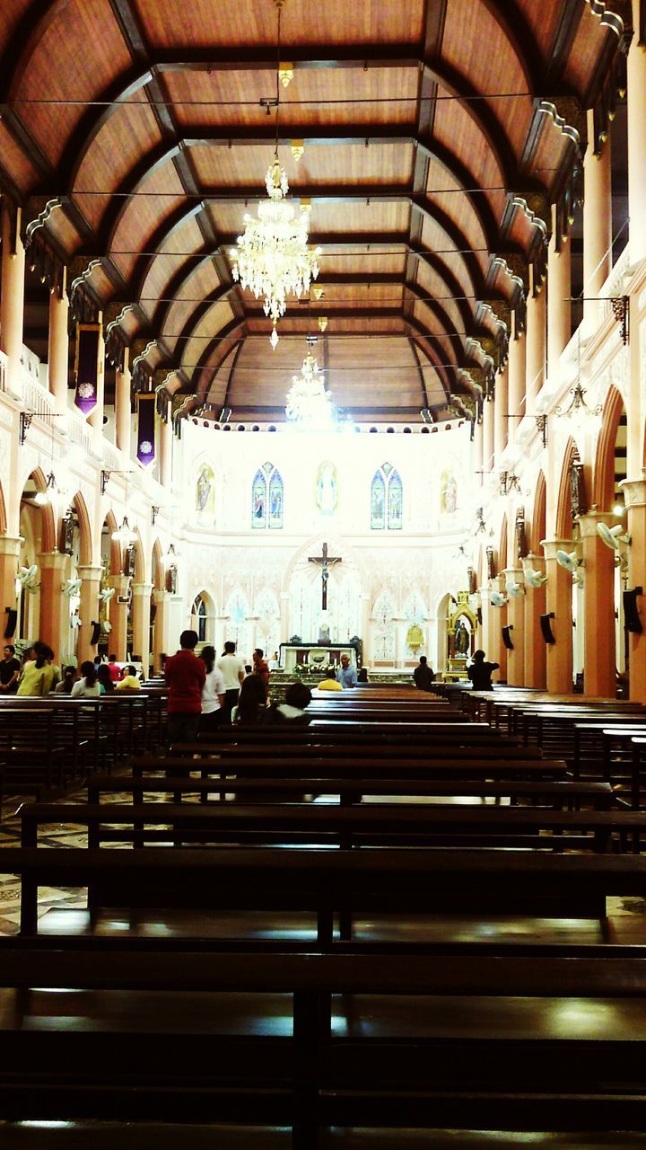 indoors, ceiling, architecture, interior, architectural column, place of worship, in a row, built structure, travel, incidental people, large group of people, religion, spirituality, hanging, men, arch, retail, public transportation, railroad station