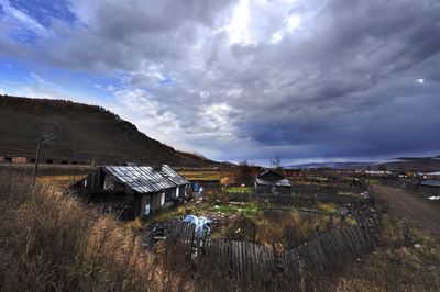 Built structure on landscape against cloudy sky