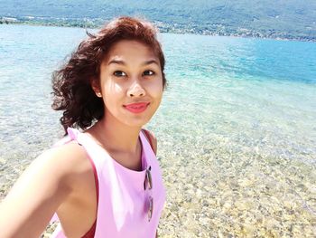 Portrait of smiling young woman standing at beach