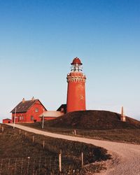 Lighthouse amidst buildings against clear blue sky