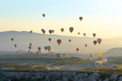 Hot air balloons flying over landscape against sky during sunset