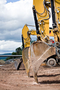 Earth mover on field against sky