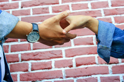 Close-up of woman hand on brick wall