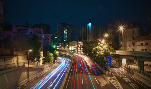 High angle view of light trails on street amidst buildings at night