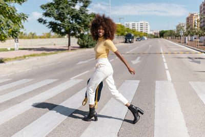 Black woman with afro hair crossing the street with a backpack in hand