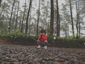 Full length of man sitting on land in forest
