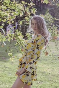 Young woman standing by tree