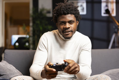 Young man using mobile phone while sitting on bed at home