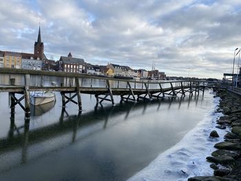 Bridge over river against sky during winter