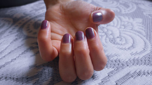 Cropped hand of woman with painted nails on bed