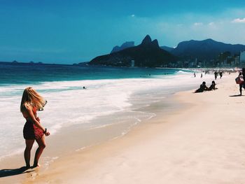 Woman standing on beach against sky