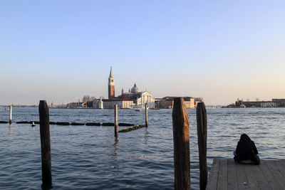 Wooden posts in sea against clear sky