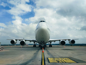 Airplane on airport runway against sky