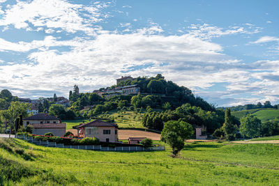 Trees and houses on field against sky