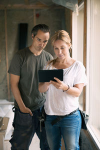 Couple using digital tablet in house being renovated