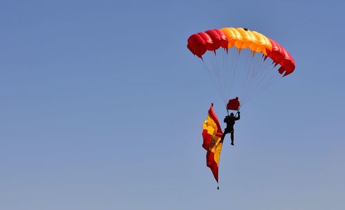 Low angle view of person paragliding against clear blue sky