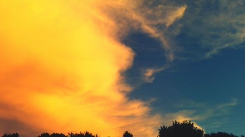 Low angle view of silhouette trees against dramatic sky