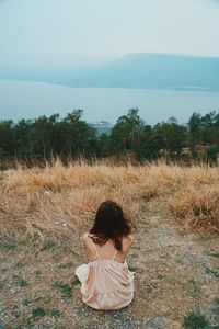 Rear view of woman sitting on field