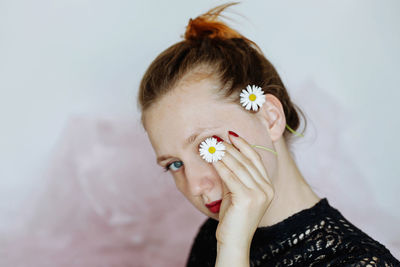 Close-up portrait of beautiful young woman holding white flower