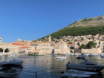 Townscape by river against clear blue sky