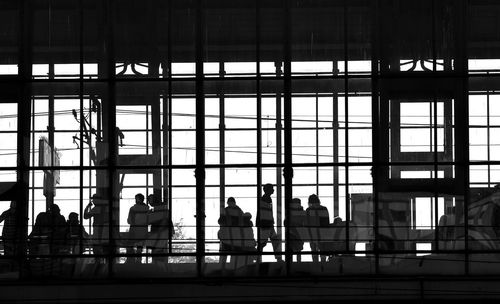 Silhouette people sitting on glass window