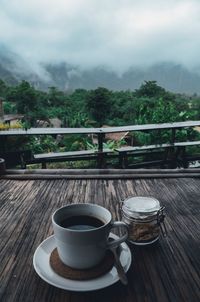 Coffee cup on table against trees