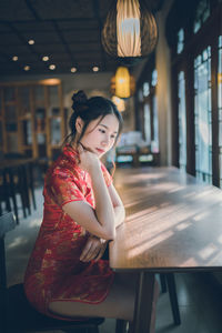 Young woman looking away while sitting at table