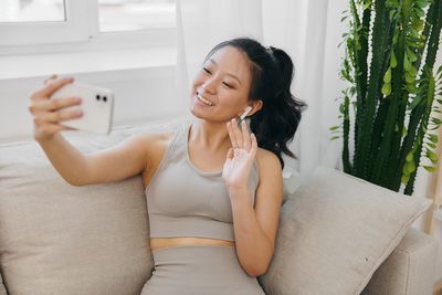 Portrait of young woman sitting on sofa at home