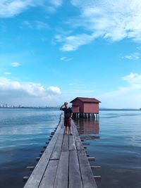 Man standing on pier over sea against sky