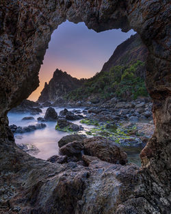 Rocks in sea against sky during sunset