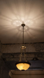 Low angle view of chandelier, with shadows cast on ceiling
